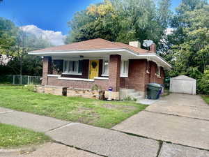 View of front of home with brick siding, a front yard, a chimney, and covered porch