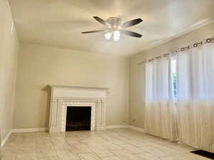 Unfurnished living room featuring a tile fireplace and ceiling fan