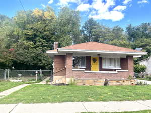 View of front of property with a porch, brick siding, a gate, and a chimney