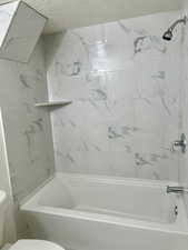 Full bath featuring tub / shower combination and a textured ceiling