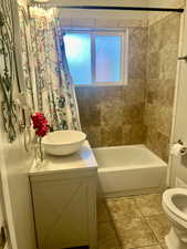 Full bathroom featuring vanity, shower / bath combo with shower curtain, and light tile patterned floors