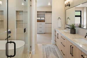 Example of full bathroom featuring a spacious closet, double vanity, and a stall shower