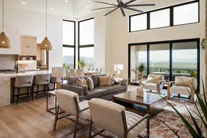 Example of living room featuring a high ceiling, light wood-style floors, recessed lighting, and a ceiling fan