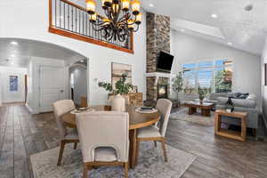 Dining space featuring a fireplace, dark wood-style floors, arched walkways, high vaulted ceiling, and recessed lighting