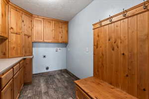 Laundry area with cabinet space, dark wood-style floors, a textured ceiling, hookup for an electric dryer, and washer hookup