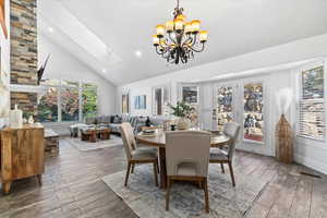 Great room featuring high vaulted ceiling, wood finished floors, a chandelier, a skylight, and recessed lighting