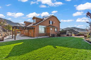 Rear view of property with a yard, a deck with mountain view, stucco siding, and a patio