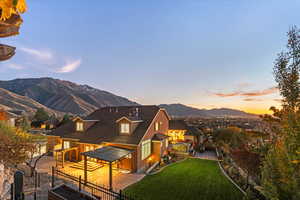 Back of house at dusk with a mountain view, a patio area, and driveway