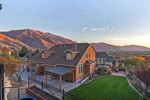 Rear view of house featuring a fenced backyard, a mountain view, a patio, and a shingled roof