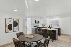 Dining area featuring a textured ceiling, light wood-style floors, and recessed lighting