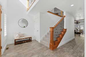 Stairway with wood finished floors, a chandelier, recessed lighting, and a towering ceiling