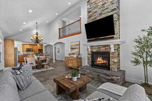 Living room with arched walkways, high vaulted ceiling, a fireplace, dark wood-type flooring, and a chandelier