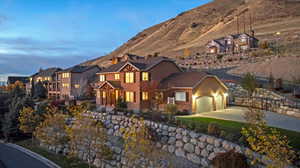View of front facade featuring stucco siding, concrete driveway, a garage, stone siding, and a mountain view