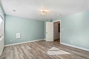 Unfurnished room with wood finished floors and a textured ceiling