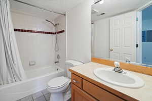 Full bathroom with shower / bathtub combination with curtain, vanity, a textured ceiling, and light tile patterned floors