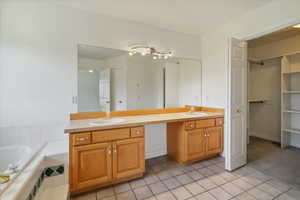 Bathroom with light tile patterned floors, double vanity, a bath, a walk in closet, and light colored carpet