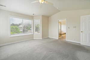 Spare room featuring carpet, vaulted ceiling, and ceiling fan