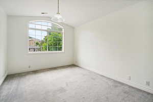 Unfurnished room featuring vaulted ceiling and carpet flooring