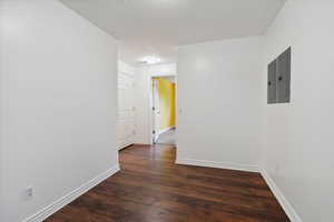 Spare room with dark wood-style flooring, a textured ceiling, and electric panel