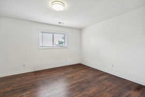 Empty room featuring dark wood-style floors and a textured ceiling