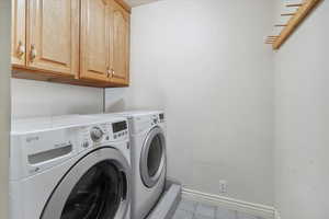 Laundry room featuring light tile patterned floors, separate washer and dryer, and cabinet space