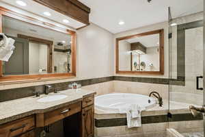 Full bath featuring a garden tub, a shower stall, vanity, recessed lighting, and tile walls