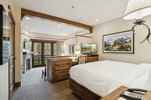 Bedroom with beamed ceiling, dark colored carpet, recessed lighting, and access to exterior