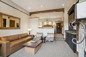 Living area featuring beamed ceiling, recessed lighting, and light carpet