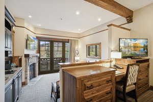 Kitchen with dark carpet, a fireplace with flush hearth, beam ceiling, recessed lighting, and an office area