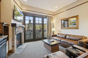 Carpeted living area with a stone fireplace and recessed lighting