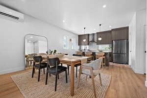 Dining area featuring light wood-style flooring, recessed lighting, and a wall unit AC