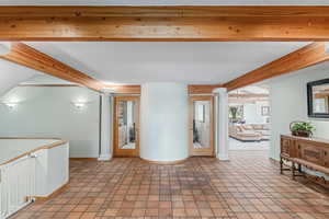Hall featuring beamed ceiling, decorative columns, and southwest tile patterned floors