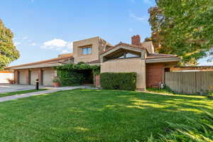 View of front facade with a chimney, stucco siding, brick siding, and driveway