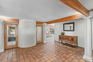 Entryway with decorative columns and beamed ceiling