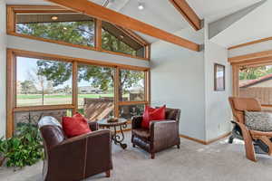 Living room with beamed ceiling, carpet floors, and high vaulted ceiling