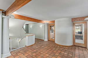 Entryway with beamed ceiling and decorative columns