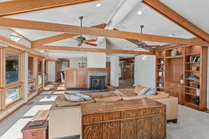 Living room with light colored carpet and a fireplace with raised hearth