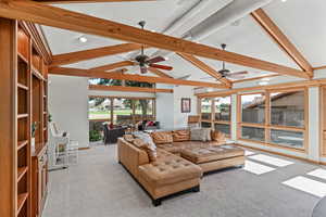 Living area featuring beam ceiling, light carpet, high vaulted ceiling, and ceiling fan