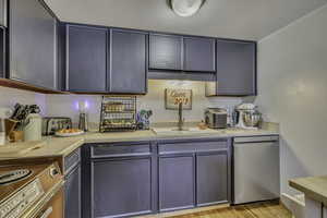 Kitchen with light countertops, dishwasher, gray cabinets, light wood finished floors, and range with electric cooktop