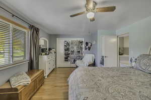 Bedroom with light wood-style floors, a closet, and a ceiling fan