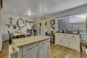 Kitchen with wood counters, light wood-type flooring, a center island, and white cabinets