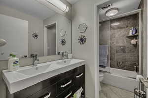 Bathroom featuring double vanity, shower / bath combination with glass door, and light tile patterned floors