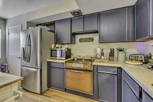 Kitchen featuring stainless steel appliances, light countertops, and light wood-style floors