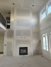 Unfurnished living room featuring a towering ceiling and a glass covered fireplace