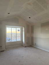Unfurnished room featuring lofted ceiling and baseboards