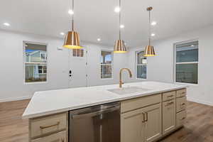 Kitchen with light wood-style floors, stainless steel dishwasher, light stone countertops, decorative light fixtures, and recessed lighting