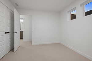 Unfurnished bedroom featuring light carpet and baseboards