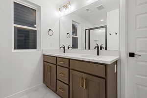 Full bathroom with double vanity, a shower stall, and light marble finish flooring