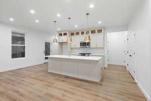 Kitchen with a center island with sink, decorative backsplash, recessed lighting, light wood-style floors, and appliances with stainless steel finishes