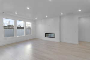 Unfurnished living room with a glass covered fireplace, light wood finished floors, and recessed lighting